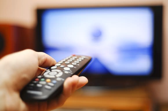 A person points a remote at a TV.