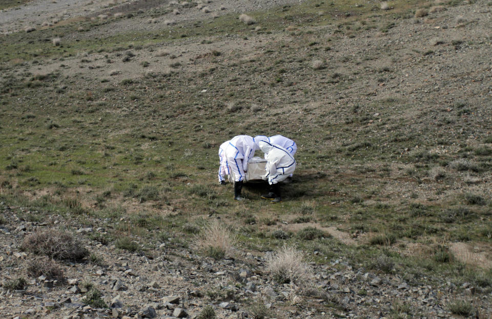 FILE - In this Friday, March 27, 2020 file photo, municipality workers bury the body of coronavirus victim on the outskirts of Herat province, west of Kabul, Afghanistan. Across the Middle East and parts of South Asia, bereaved families have faced traumatic restrictions on burying their dead amid the pandemic. Religion and customs that require speedy burials in the largely Muslim region have clashed with fears of COVID-19 contagion and government-mandated lockdowns. (AP Photo/Hamed Sarfarazi, File)