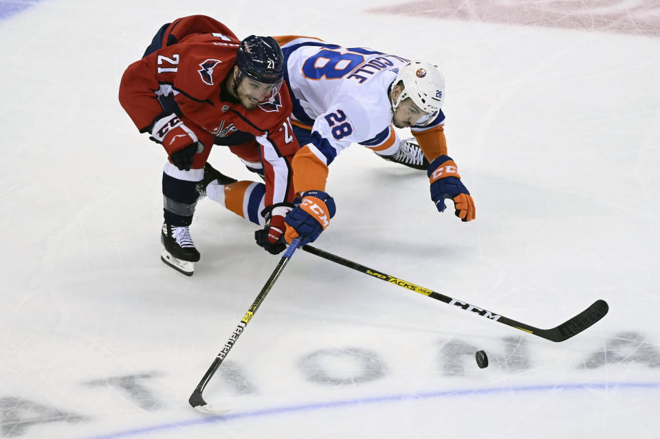 Washington Capitals right wing Garnet Hathaway (21) and New York Islanders left wing Michael Dal Colle (28) reach for the puck during first-period NHL Eastern Conference Stanley Cup playoff hockey game action in Toronto, Thursday, Aug. 20, 2020. (Nathan Denette/The Canadian Press via AP)