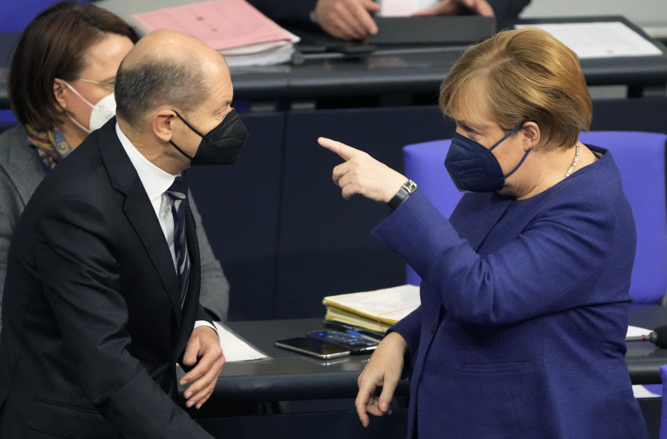 German Chancellor Angela Merkel, right, and SPD candidate for chancellor Olaf Scholz talk during a parliament Bundestag session about new measures to battle the coronavirus pandemic at the Reichstag building in Berlin, Germany, Thursday, Nov.18, 2021. (AP Photo/Markus Schreiber)