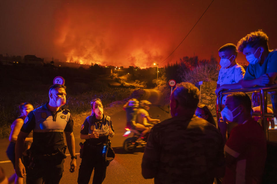 Local residents try to reach their houses in Benijos village as police block the area as fire advances in La Orotava in Tenerife, Canary Islands, Spain on Saturday, Aug. 19, 2023. Firefighters have battled through the night to try to bring under control the worst wildfire in decades on the Spanish Canary Island of Tenerife, a major tourist destination. The fire in the north of the island started Tuesday night and has forced the evacuation or confinement of nearly 8,000 people. (AP Photo/Arturo Rodriguez)