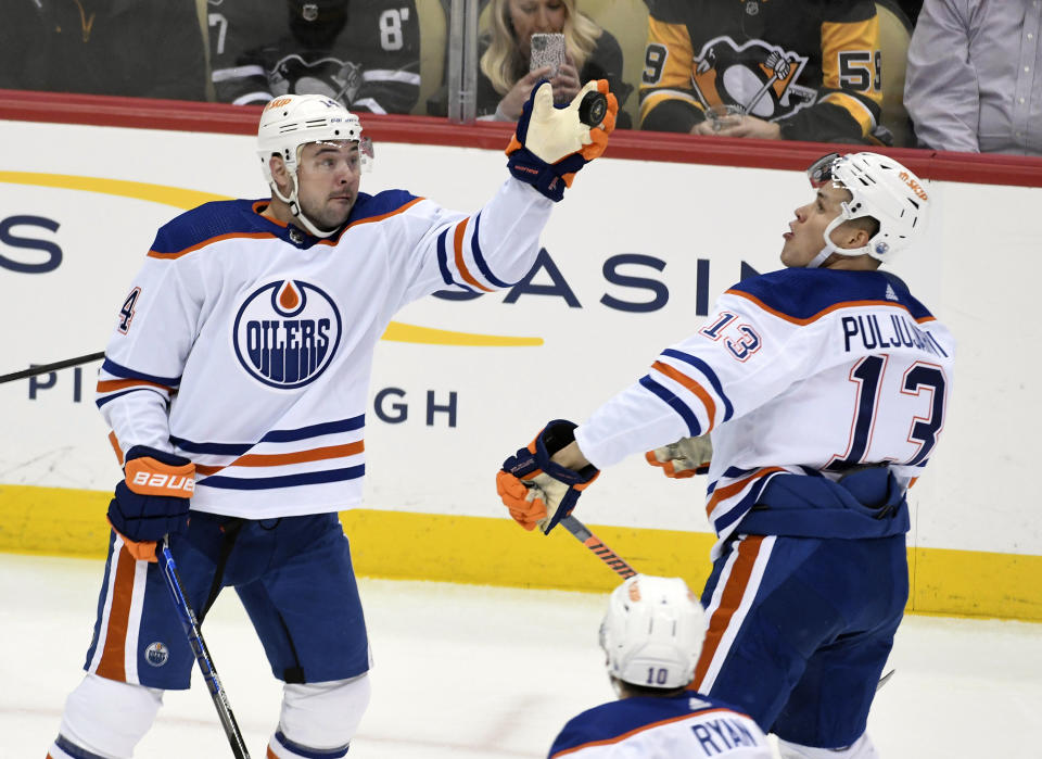 Edmonton Oilers center Devin Shore (14) reaches for the puck near right wing Jesse Puljujarvi (13) as they play the Pittsburgh Penguins during the first period of an NHL hockey game, Thursday, Feb. 23, 2023, in Pittsburgh. (AP Photo/Philip G. Pavely)