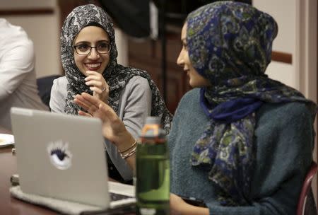 University of California Riverside student Amal Ali (L), 22, and University of California Irvine student Huda Herwees, 19, watch the Republican presidential debate with other students at the Council on American-Islamic Relations (CAIR) office in Anaheim, California December 15, 2015. REUTERS/Jason Redmond