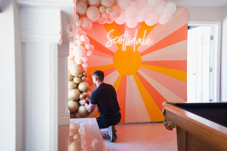 Scottsdale Bachelorette owner and founder, Casey Hohman, sets up a photo backdrop in an Airbnb for a client's bachelorette party on July 7, 2022, in Scottsdale.