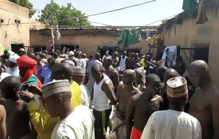 Police officers, journalists and a traditional chief stand next to people who were rescued by police in Sabon Garin, in Daura local government area of Katsina state