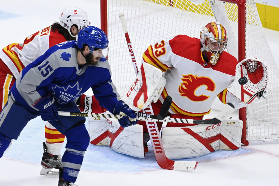 Calgary Flames goaltender David Rittich (33) makes a save as Toronto Maple Leafs center Alexander Kerfoot (15) and Flames defenseman Christopher Tanev (8) battle in front during second period NHL action in Toronto on NHL hockey action in Toronto on Wednesday, Feb. 24, 2021. (Frank Gunn/The Canadian Press via AP)