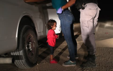 A two-year-old Honduran asylum seeker cries as her mother is searched and detained near the US-Mexico border on June 12 - Credit: John Moore/Getty