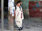 An Afghan man with bloodstained clothes stands at the side of blast after a suicide attack in Kabul, Afghanistan July 23, 2016. REUTERS/Omar Sobhani