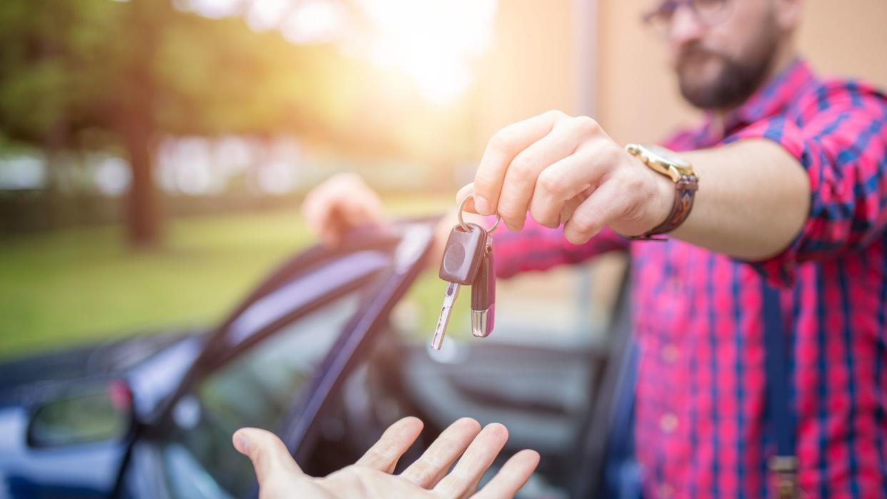 Man standing by the car and giving back car keys