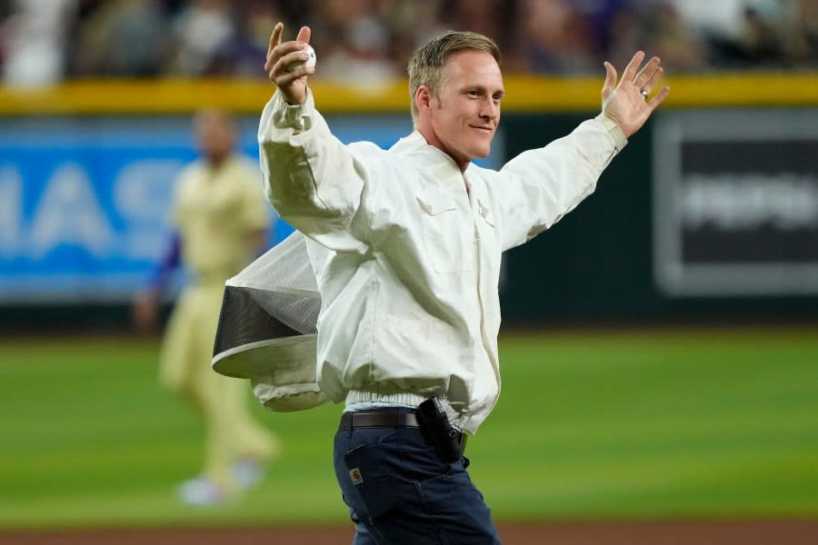 Bee keeper Matt Hilton prepares to throw out the ceremonial first pitch prior to a baseball game between the Los Angeles Dodgers and the Arizona Diamondbacks, Tuesday, April 30, 2024, in Phoenix. Hilton removed a swarm of bees on the net behind home plate that delayed the start of the game. (AP Photo/Matt York)