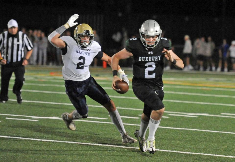 Hanover's David Quinlan, left, chases down Duxbury quarterback Matt Festa on a keeper during the high school football season opener at Duxbury High School, Thursday, Sept. 8, 2022.