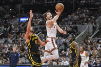 San Antonio Spurs' Cedi Osman, center, goes to the basket against Golden State Warriors' Klay Thompson (11) during the first half of an NBA basketball game Sunday, March 31, 2024, in San Antonio. (AP Photo/Darren Abate)