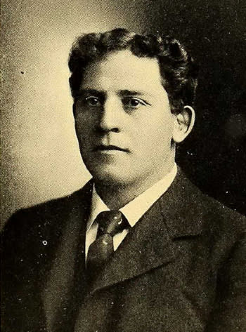 A young Amos Alonzo Stagg looks slightly off camera in a coat and tie with short, wavy hair.