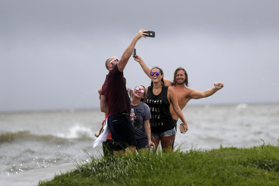 Daniel LeBlanc takes a selfie photo with friends Erin Shaw, second left, Brittany Schanzbach and Chris Baker, right, in front of waves from a storm surge in New Orleans, Sunday, June 7, 2020, as Tropical Storm Cristobal approaches the Louisiana Coast. (AP Photo/Gerald Herbert)