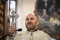 In this photo taken on Sunday, May 24, 2020, Father Vasyl Gasynets, Ukrainian Greek Catholic Church priest conducts a religion service at the church in Chernivtsi. Gasynets has returned to conducting services at his Greek Catholic church in priestly raiment, but wearing a mask while distributing communion. (AP Photo/Evgeniy Maloletka)