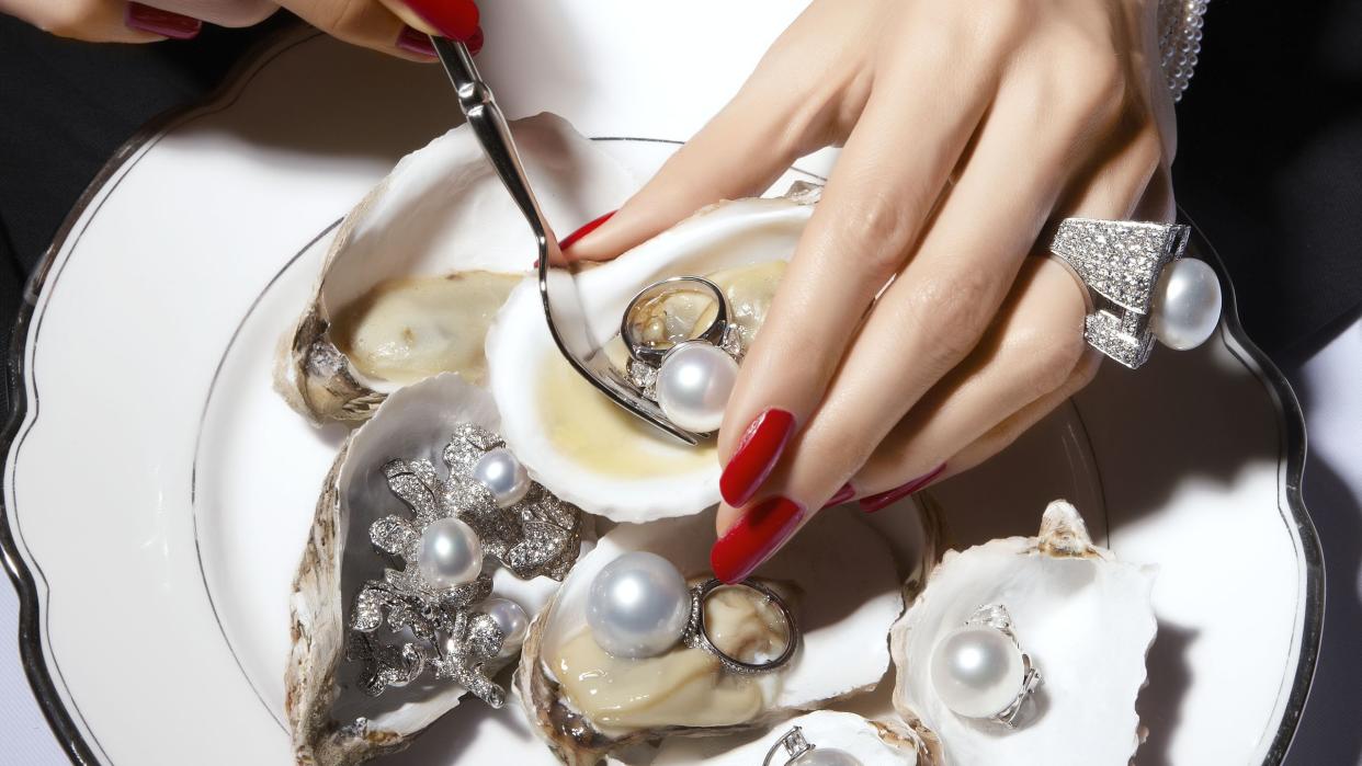 woman with red nail polish eating oysters with pearls inside