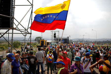 A pro-government supporter waves a Venezuelan flag during a gathering at the Tienditas cross-border bridge between Colombia and Venezuela for a three-day event to compete against the Richard Branson-backed concert for Venezuela aid, in Tienditas, Venezuela February 22, 2019. REUTERS/Marco Bello