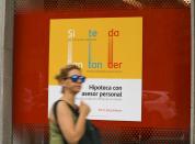Woman walks past a mortgage advertisement at a Santander bank branch in Madrid