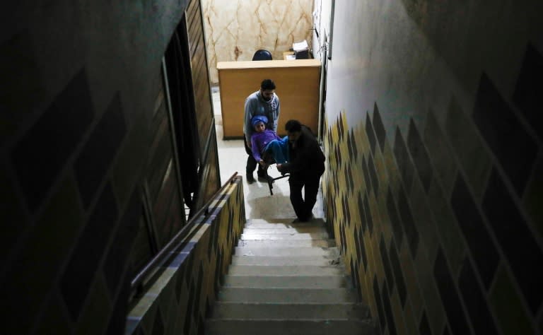 Two men carry 14-year-old Dania, who suffers from renal insufficiency, to have her dialysis inside a basement-turned-clinic in the rebel-held Syrian town of Douma, on the outskirts of the capital Damascus, on March 16, 2017