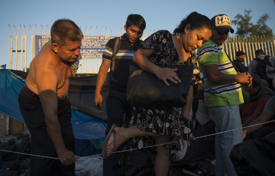 A man helps a fellow migrant woman cross from one section to another as Central Americans organize themselves into blocks, to be attended by Mexican migration authorities, on a bridge that stretches over the Suchiate River, connecting Guatemala and Mexico, in Tecun Uman, Guatemala, Monday, Oct. 22, 2018. While thousands of Central American migrants are advancing toward the U.S. border in a caravan, some stayed behind to try to enter Mexico legally. (AP Photo/Oliver de Ros)