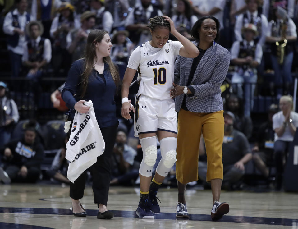 California's Jazlen Green (10) is assisted off the court by coach Charmin Smith, right, and a trainer in the first half of an NCAA college basketball game against Stanford, Sunday, Jan. 12, 2020, in Berkeley, Calif. (AP Photo/Ben Margot)