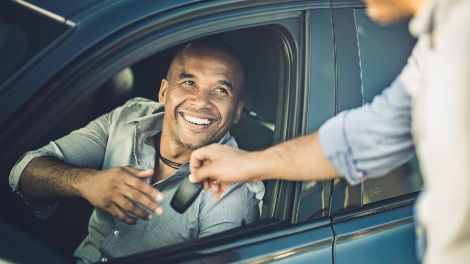 Happy African American businessman taking car keys from a sales person.