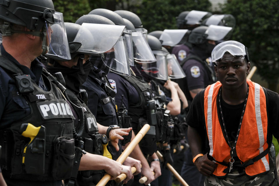 A protestor marches by a police line in downtown Louisville, Kentucky, on September 23, 2020. (Photo by JEFF DEAN/AFP via Getty Images)