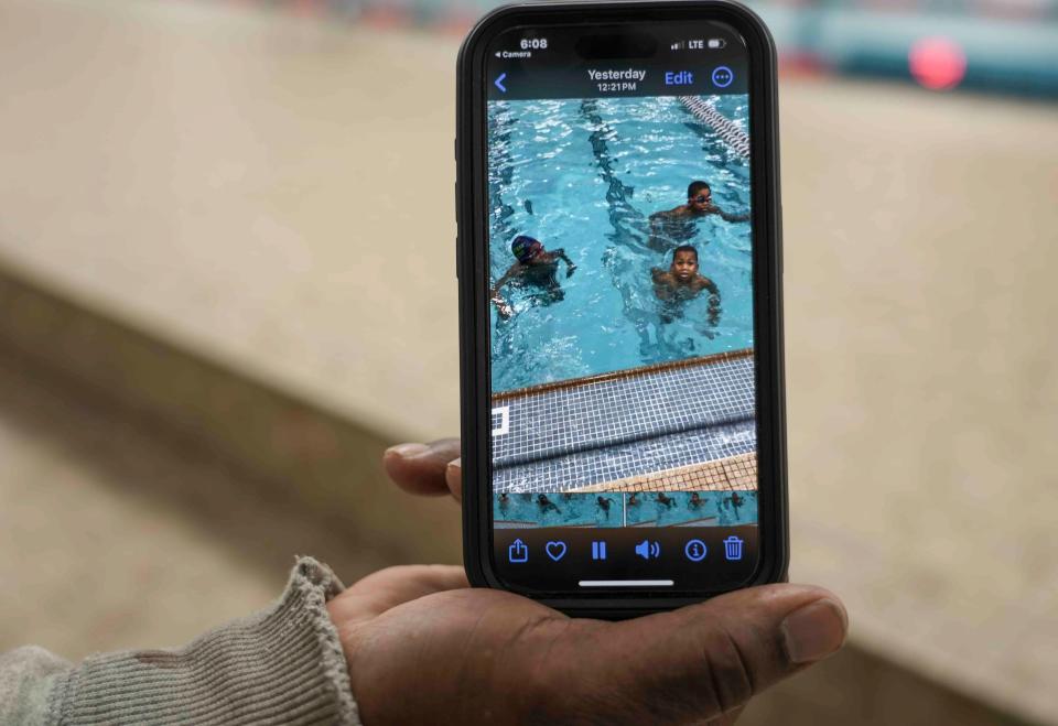 Eric Blue shows a photo of his three grandsons in the pool Monday, Jan. 29, 2024, at Riverside High School pool in Milwaukee. He takes his grandsons swimming twice a week.