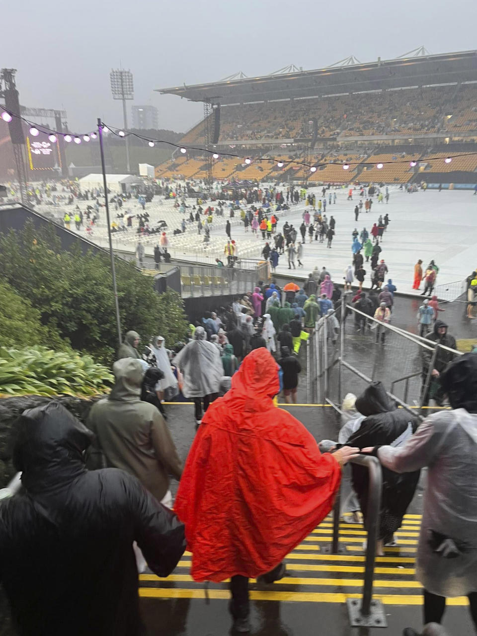 Fans leave Mt Smart Stadium in Auckland, New Zealand, Friday, Jan. 27, 2023, where about 40,000 people were expected to attend an Elton John concert. Torrential rain and wild weather in Auckland causes disruptions throughout the city and an Elton John concert to be canceled just before it was due to start. (Julea Dalley/New Zealand Herald via AP)