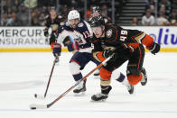 Anaheim Ducks' Max Jones (49) moves the puck past Columbus Blue Jackets' Johnny Gaudreau (13) to score a goal during the third period of an NHL hockey game Friday, March 17, 2023, in Anaheim, Calif. (AP Photo/Jae C. Hong)