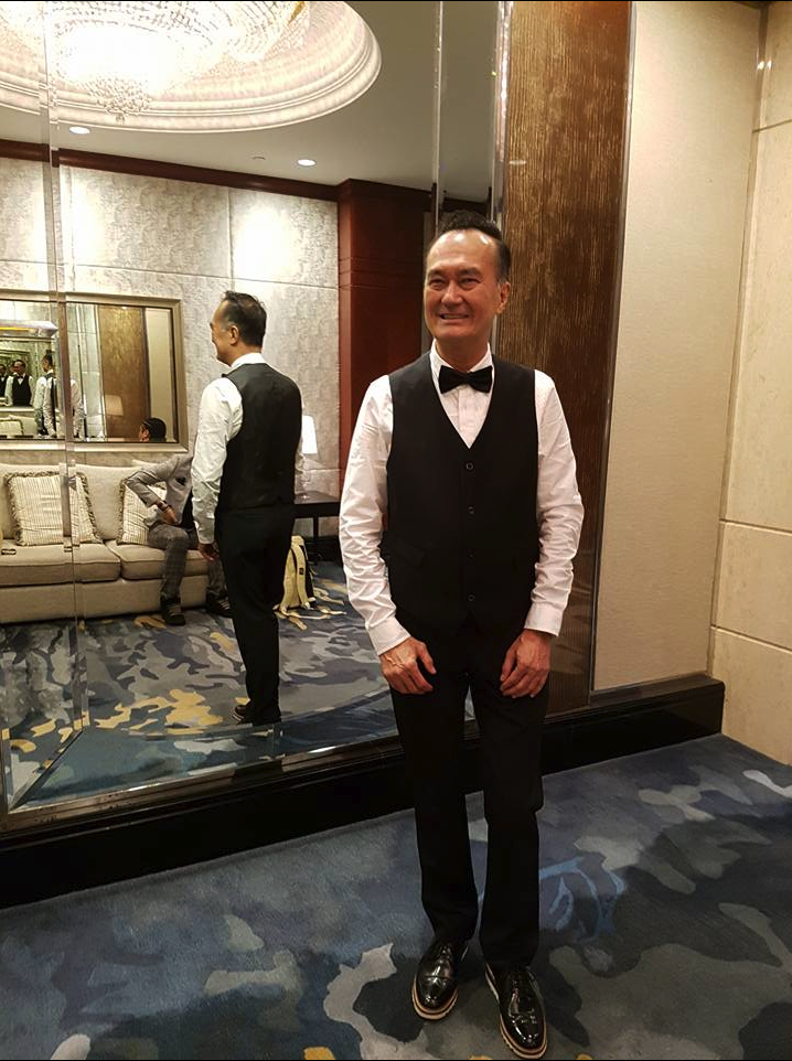 Real estate icon Dennis Wee poses for a photo in formal attire.