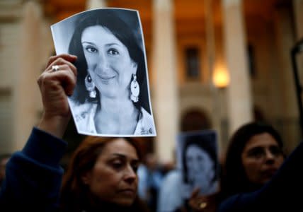 FILE PHOTO: People hold up pictures of assassinated anti-corruption journalist Daphne Caruana Galizia during a vigil and demonstration marking seven months since her murder in a car bomb, at her makeshift memorial outside the Courts of Justice in Valletta, Malta May 16, 2018.  REUTERS/Darrin Zammit Lupi/File Photo