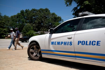 Two men walk in front of a police car the day after violent clashes between police and protesters broke out on streets overnight in Memphis