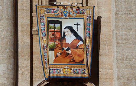 The tapestry of Elisabetta Della Santissima Trinita Catez, one of the seven new saints, hangs from Saint Peter's Basilica before the start of a canonization mass led by Pope Francis at the Vatican October 16, 2016. REUTERS/Tony Gentile