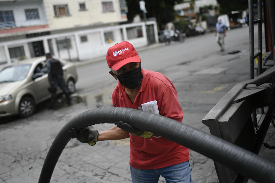 A worker wearing a face mask amid the new coronavirus pandemic works to fills up one of the tanks of a state oil company gas station in Caracas, Venezuela, Sunday, May 31, 2020. After decades of being the cheapest gasoline in the world, Venezuelan President Nicolas Maduro indicates that as of next Monday a new pricing scheme will be imposed on some 200 stations. (AP Photo/Matias Delacroix)