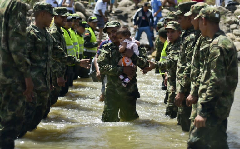 A baby is carried across the Tachira River by a soldier as hundreds of Colombians leave Venezuela with their belongings, arriving in Cucuta, Colombia on August 27, 2015