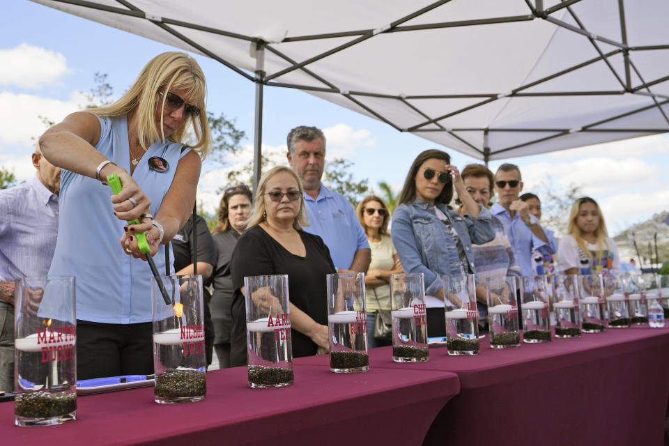 Annika Dworet, left, mother of shooting victim Nicholas Dworet, lights a candle for him, Tuesday, Feb. 14, 2023, at a ceremony in Coral Springs, Fla., honoring the lives of the 17 students and staff of Marjory Stoneman Douglas High School that were killed on Valentine's Day, 2018. (AP Photo/Wilfredo Lee)