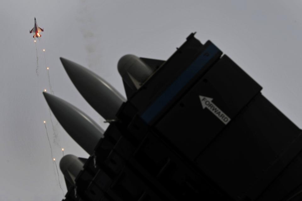Spyder surface-to-air missiles on a static display are seen as an F-16 jet fires flares