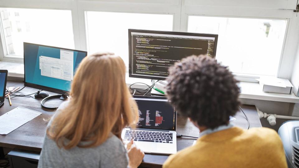 Rear view of male and female computer programmers working on a new project together in office.