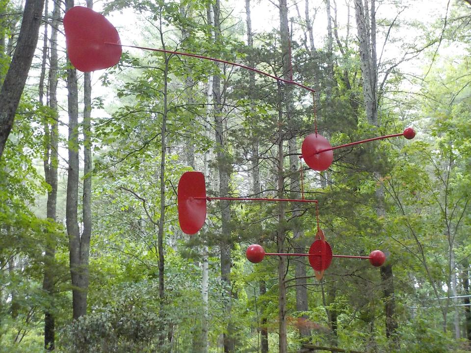 Sculpture in the woods enhances the display at Bedrock Gardens in New Hampshire.