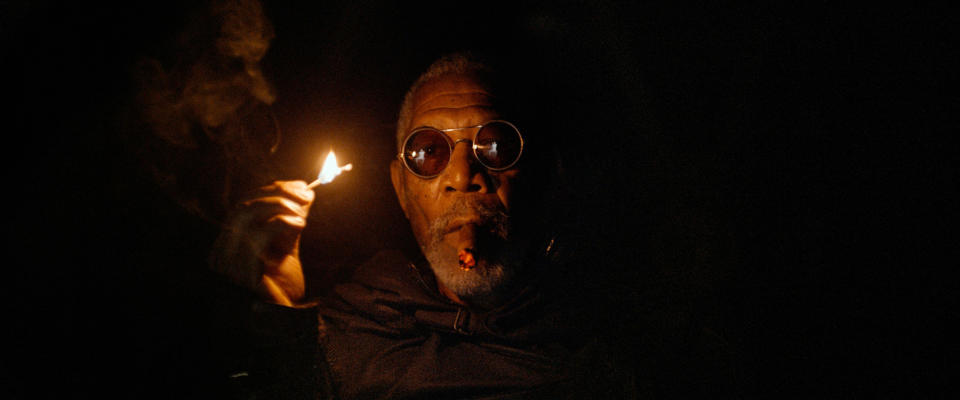 a character in circular glasses lights a match in a dark room