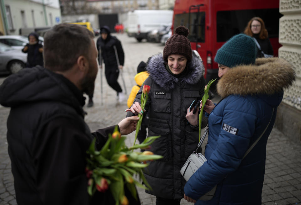 Polish Catholic priest Cordian Szwarc hands tulips to two women who have fled Ukraine, in recognition of International Women's Day at the train station in Przemysl, Poland, Tuesday, March 8, 2022. U.N. officials said Tuesday that the Russian onslaught has forced 2 million people to flee Ukraine. It has trapped others inside besieged cities that are running low on food, water and medicine amid the biggest ground war in Europe since World War II. (AP Photo/Daniel Cole)