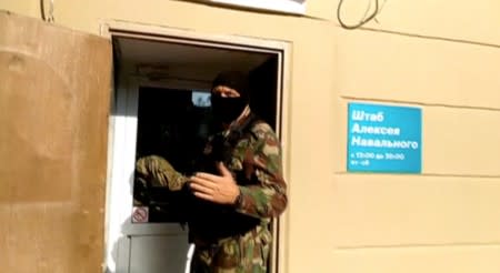 A still image shows a masked law enforcement officer during a raid in an office of Kremlin critic Navalny in Perm