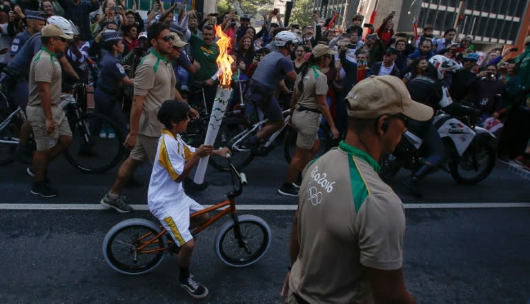 A resident of Sao Paulo carries the Olympic torch through the streets of Sao Paulo on July 24, 2016