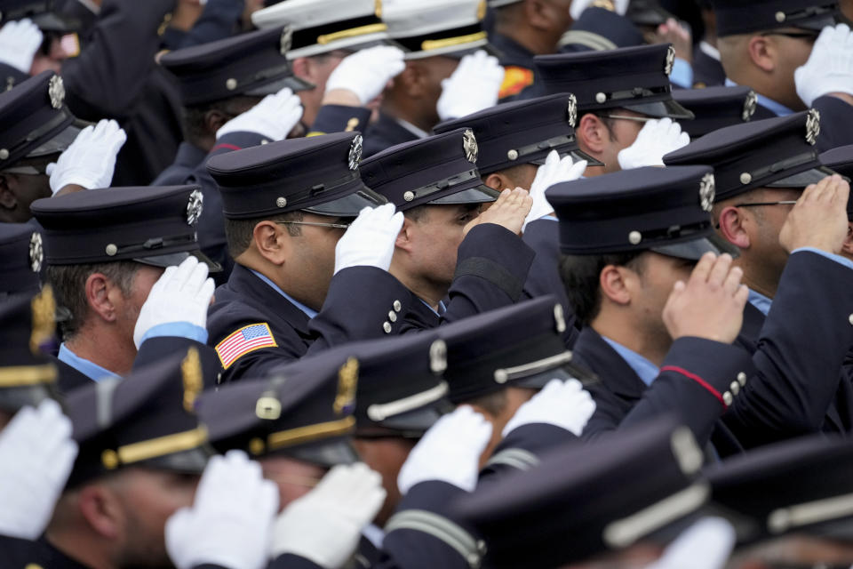 Members of various emergency services salute as the casket of Newark firefighter Augusto "Augie" Acabou departs aboard a firetruck hearse after being carried from the Cathedral Basilica of the Sacred Heartvduring his funeral days after he died battling a fire aboard the Italian-flagged Grande Costa d'Avorio cargo ship at the Port of Newark, Thursday, July 13, 2023, in Newark, N.J. The fire also claimed the life of Wayne "Bear" Brooks Jr. (AP Photo/John Minchillo)