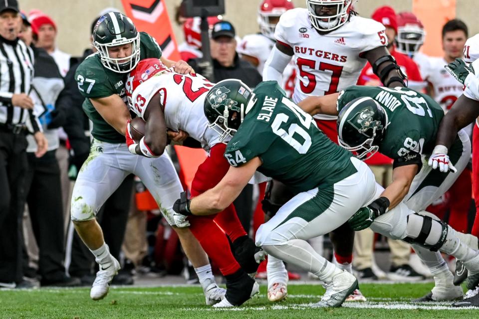 Michigan State's Cal Haladay, left, and Jacob Slade, right, tackle Rutgers' Kyle Monangai during the first quarter on Saturday, Nov. 12, 2022, in East Lansing.