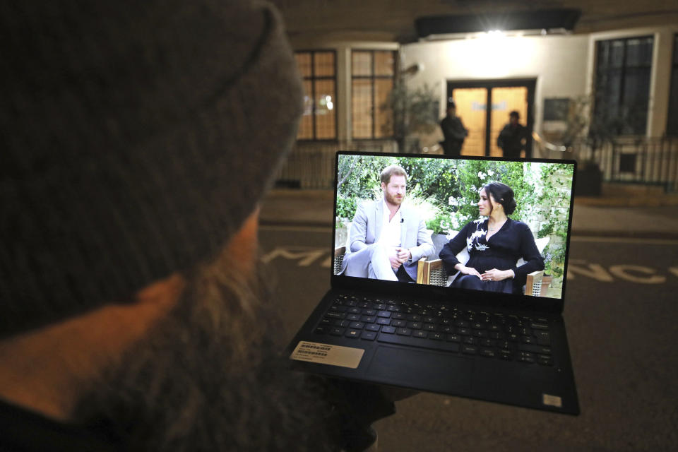 A man watches his laptop showing an interview of Prince Harry and Meghan, The Duchess of Sussex, by Oprah Winfrey outside King Edward VII's Hospital where the Duke of Edinburgh has been transferred from a specialist cardiac hospital to a private facility to continue his recovery after a heart procedure, in London Monday, March 8, 2021. (Yui Mok/PA via AP)