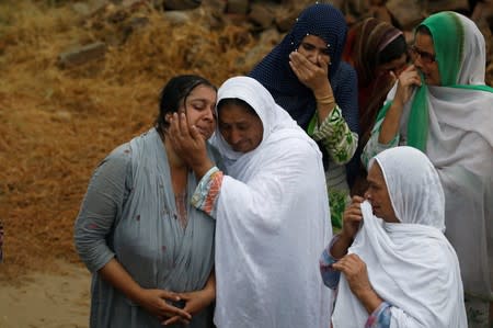 A relative comforts the mother of a two and half year-old Mohammad Bilal Sajid, who was killed in an earthquake, during his funeral in Jatlan, Mirpur