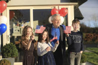 Joe Biden's cousins Brendan Blewitt with his grandchildren Emily, Lauren, and Darragh wave their U.S. flags to the media from their home in Knockmore, near the town of Ballina in Ireland, Wednesday, Jan. 20, 2021. Biden has officially become the 46th president of the United States. His great-great grandfather Patrick Blewitt was born in, County Mayo, in 1832. He left for the US in 1850, aged 18. (AP Photo/Peter Morrison)