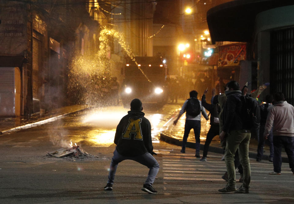 Un policía rocía agua a manifestantes durante una protesta contra la eventual reelección del presidente Evo Morales en La Paz, Bolivia, el martes 5 de noviembre de 2019. (AP Foto/Juan Karita)